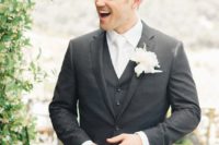 22 a graphite grey three-piece wedding suit with a white shirt, tie and a white floral boutonniere for a formal look