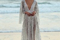 22 a sparkling fully embellished wedding dress with bell sleeves and a train plus a plunging neckline