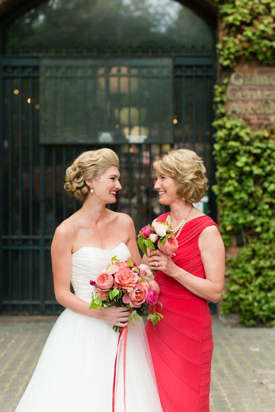 a bold fuchsia draped sheath dress without sleeves and with a pearl necklace for a colorful wedding