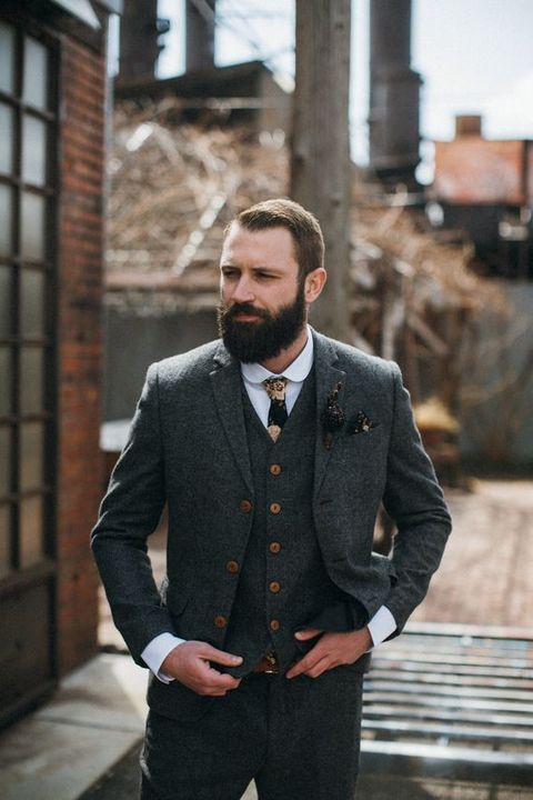 a vintage-inspired dark grey three-piece wedding suit with brown buttons and a dark floral tie