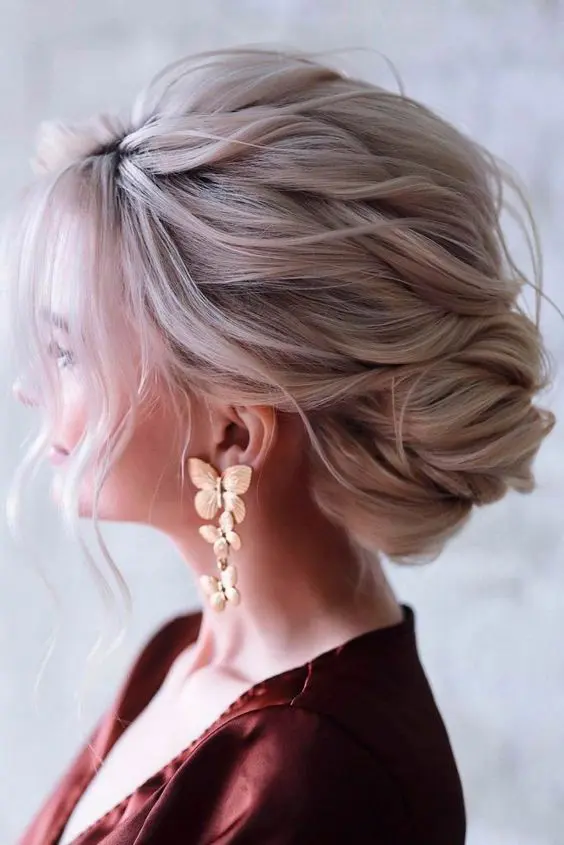 a beautiful and dimensional low French twisted updo with a wavy and textural top and some waves down is awesome