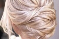 a beautiful blonde twisted low chignon with a bump on top and some locks down is a chic and formal idea