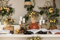 a beautiful rustic wedding station with greenery and lemon arrangements, pillar candles, crates and baskets with lemons all around