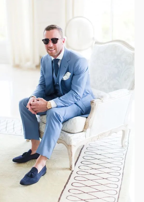 A bold blue three piece suit with a white shirt, a navy tie and navy moccasins and no socks