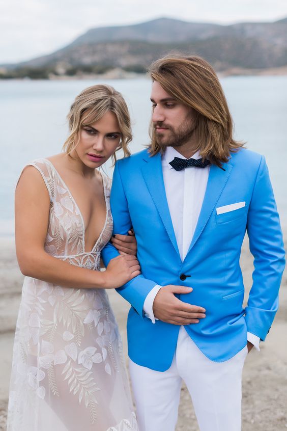 a bright and catchy coastal groom's look with a white shirt, a bold blue blazer, white trousers, a black bow tie