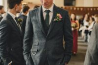a chic grey groom’s outfit with a white shirt, a green tie, a chain and a bright flower boutonniere