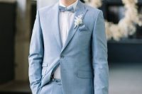 a chic groom’s look with a light blue suit, a white shirt, a light blue bow tie and a boutonniere is amazing