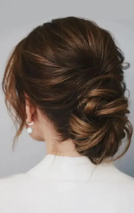 A chic low ballerina bun with a bump on top and face framing locks is a cool idea for a wedding