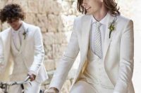 a chic white three-piece suit, a white shirt, a striped tie and a boutonniere are a super cool combo for an elegant wedding