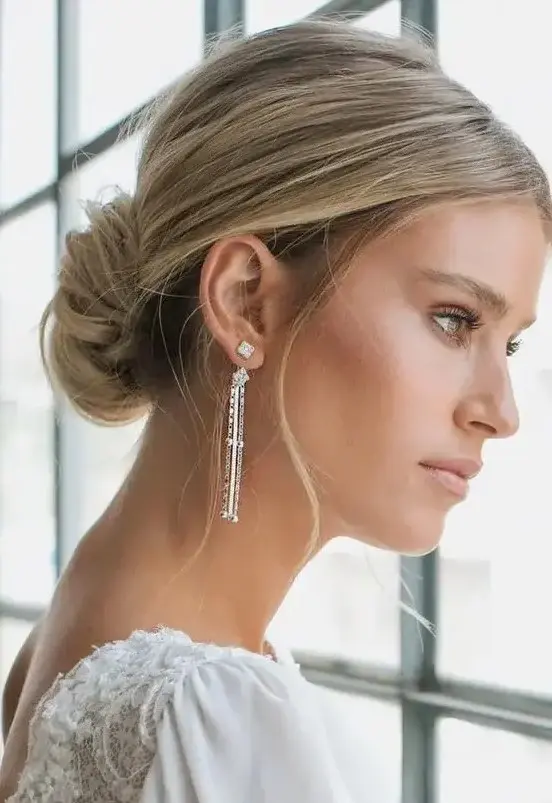 a classic low chignon with a volume on top and some locks down is a beautiful and cool hairstyle for a modern refined wedding
