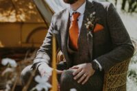 a cool boho groom’s look with a grey three-piece suit, a white shirt, an orange tie and a handkerchief plus a dried flower boutonniere