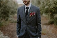 a cool fall groom’s look with a grey three-piece pantsuit, a white shirt, a black tie and a bold boutonniere