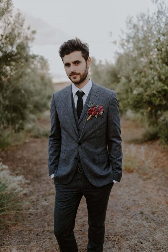 a cool fall groom's look with a grey three-piece pantsuit, a white shirt, a black tie and a bold boutonniere