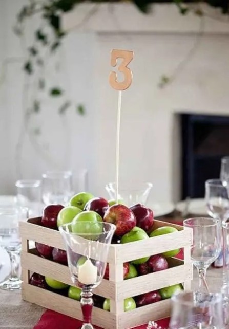 a crate with colorful apples and a table number is a lovely wedding centerpiece for a rustic wedding, and it can be done in minutes