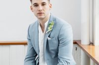 a delicate blue grey suit, a white shirt with no tie, a boutonniere for a relaxed and effortlessly chic look