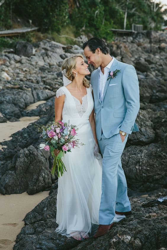 a delicate coastal groom's look with a light blue suit, a white shirt, brown shoes and a boutonniere is amazing