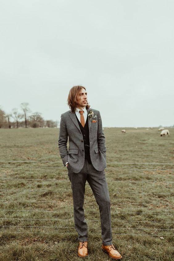 a fall groom's outfit with a grey pantsuit, a black waistcoat, a white shirt, a rust tie and amber shoes