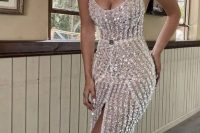 a fitting spaghetti strap fully beaded wedding dress with a deep scoop neckline and a front slit plus a train for a glam bride