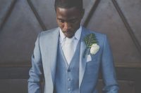 a formal groom’s look with a blue three-piece suit, a white shirt and a tie plus a whimsical boutonniere