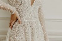 a fully embellished A-line wedding dress with a V-neckline, long sleeves is a super glam and chic idea