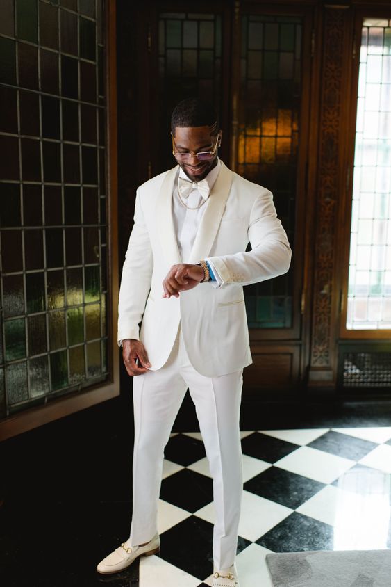 a glam groom's outfit with a white tux, a white and a bow tie, white loafers and a chain is amazing for summer