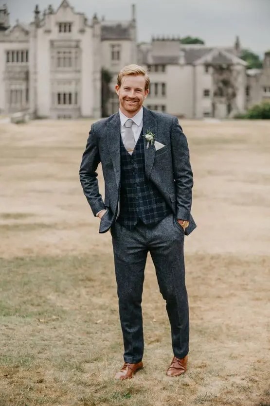 a grey tweed suit, a white shirt, a grey and navy waistcoat, a grey tie and brown shoes are a great combo