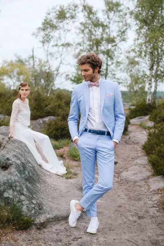 a light blue suit, a bright blue belt, a white shirt and sneakers and a pink printed bow tie