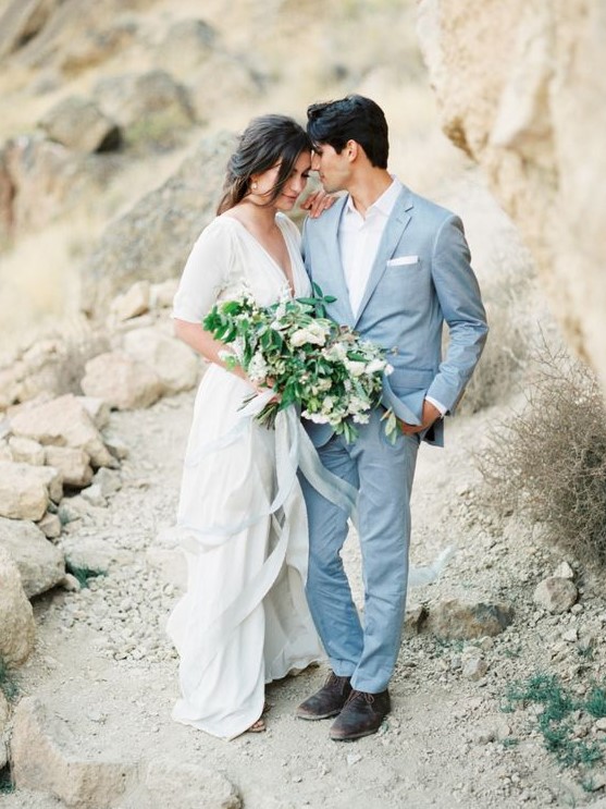 a light blue suit paired with a white shirt is a cool effortlessly chic groom's look for a coastal or beach wedding