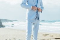 a light blue three-piece suit, a white shirt, a neck tie, brown shoes and a man bun for a coastal groom’s look