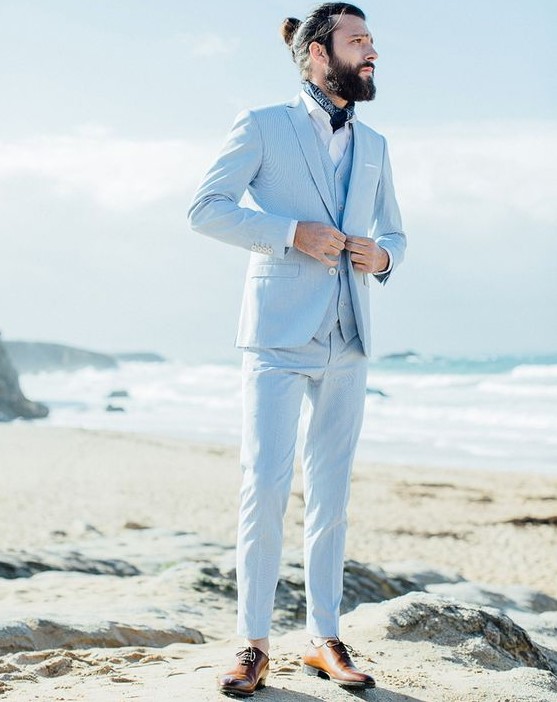 a light blue three-piece suit, a white shirt, a neck tie, brown shoes and a man bun for a coastal groom's look
