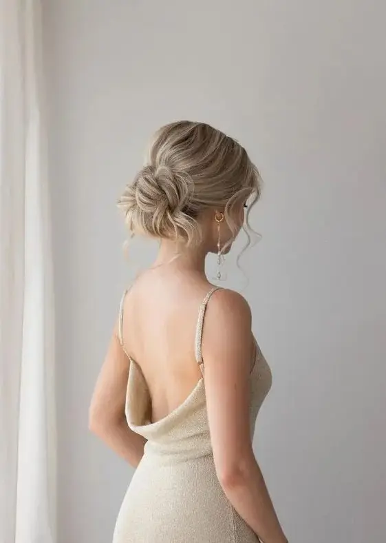 a messy and chic low updo with a bump on top and some waves down is an elegant and beautiful hairstyle