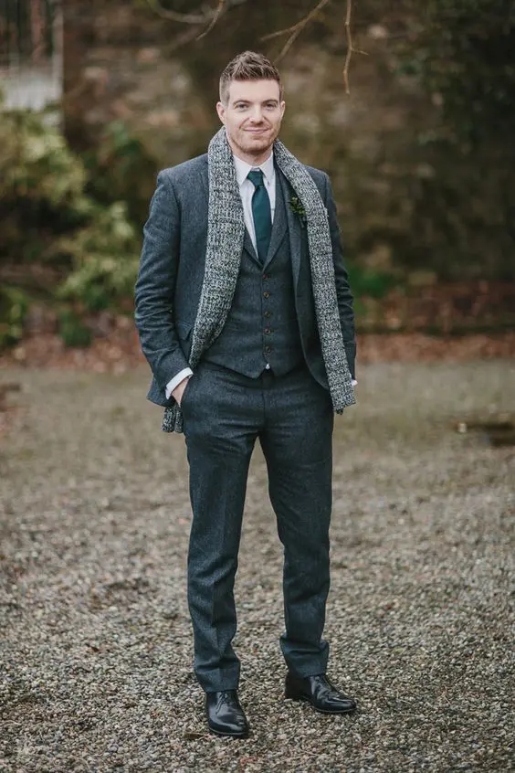 a modern fall or winter groom's look with a three-piece pantsuit, a white shirt and a green tie plus black shoes and a scarf