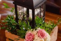 a pallet box with greenery, flowers and a black metal candle lantern for a rustic wedding