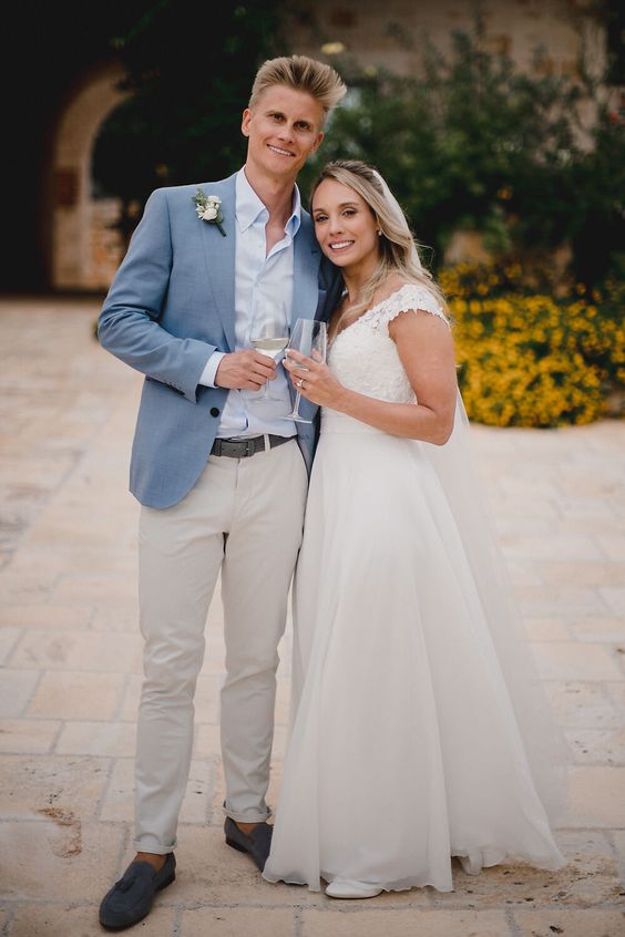 a relaxed coastal grooms look with a light blue shirt a blue grey blazer grey trousers grey loafers and a boutonniere is cool (photo by MIKI Studios - Ash Davenport)
