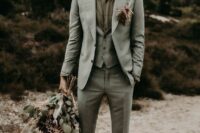 a relaxed groom’s look with a ligth grey three-piece pantsuit, a green shirt and a bright boutonniere