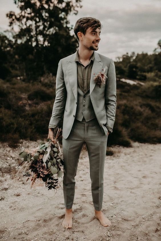 a relaxed groom's look with a ligth grey three-piece pantsuit, a green shirt and a bright boutonniere