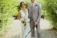 a relaxed light grey groom’s look with a three-piece pantsuit, brown shoes and a grey tie, a boutonniere for spring or summer