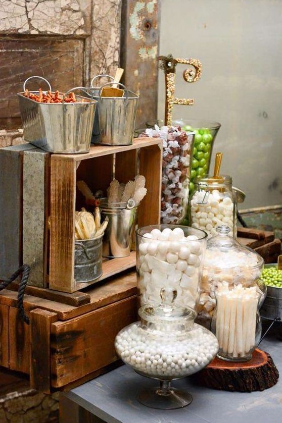 a rustic candy bar with crates, metal buckets, wood slice stands and jars with candies is a lovely idea for a rustic wedding