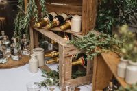 a rustic wedding champagne bar with crates, greenery, wooden cutting boards, greenery and champagne bottles and glasses