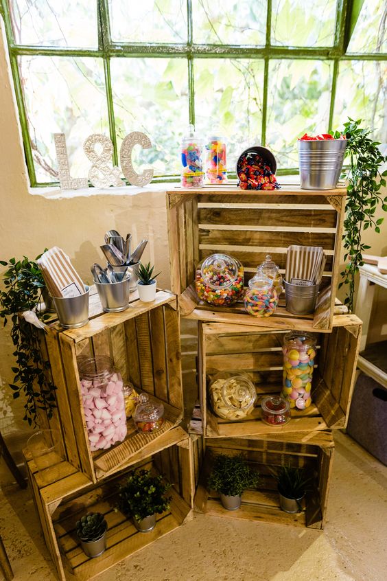 a simple and relaxed candy bar of crates, greenery in pots and some candies in jars will be a nice idea for a rustic wedding
