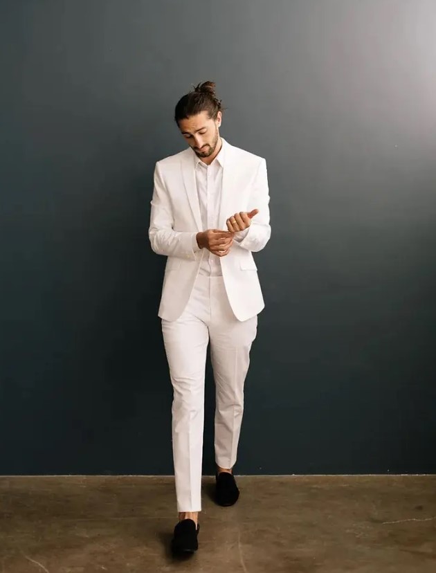 a stylish and all-minimal groom's outfit with a white suit and a shirt plus black velvet loafers is a lovely solution