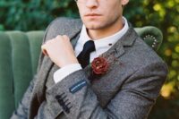 a vintage groom’s outfit with a grey tweed three-piece suit, a white shirt, a black tie and stylish glasses