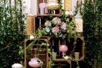 a wedding candy bar of crates, with greenery, pink blooms and soem candies in jars is amazing for a wedding