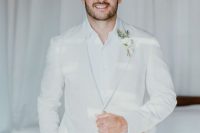 a white groom’s look with a suit, a white shirt and a boutonniere is a great idea for spring or summer