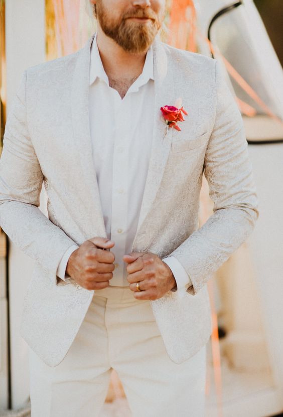 a white patterned suit, a white shirt and a red rose boutonniere are a super chic combo for a glam wedding