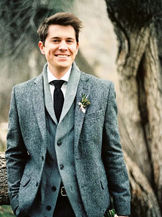 a winter groom look with a tweed jacket, a grey cardigan, a white shirt and a black tie for comfort and coziness