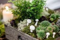 a woodland wedding centerpiece of a crate with moss, succulents, greenery and mushrooms is a lovely idea