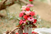a woodland wedding decoration of a crate, pinecones, branches and a bold floral arrangement