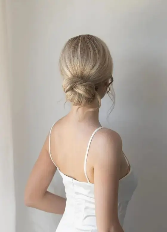 a woven low bun with a sleek yet dimensional top and waves down is a stylish and elegant idea for a wedding