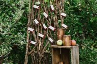 an apple orchard wedding seating plan with lots of branches, greenery and berries and some escort cards, crates with apples around